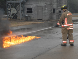 Firefighter spraying Flame Freeze through the middle of a Class B fire.